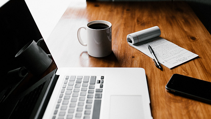 Computer with notepad and cup of coffee