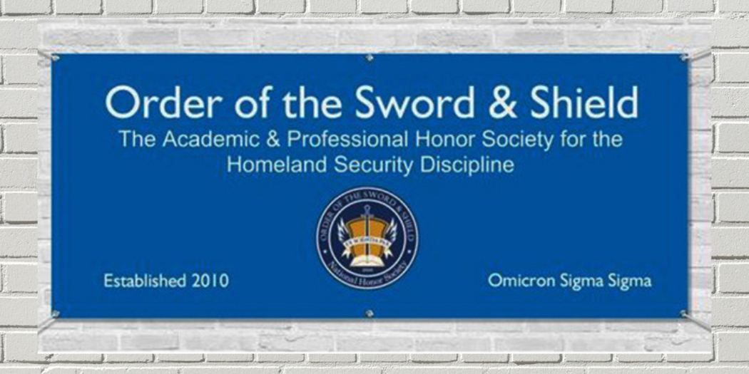 Order of the Sword and Shield banner hanging on a brick wall at Angelo State