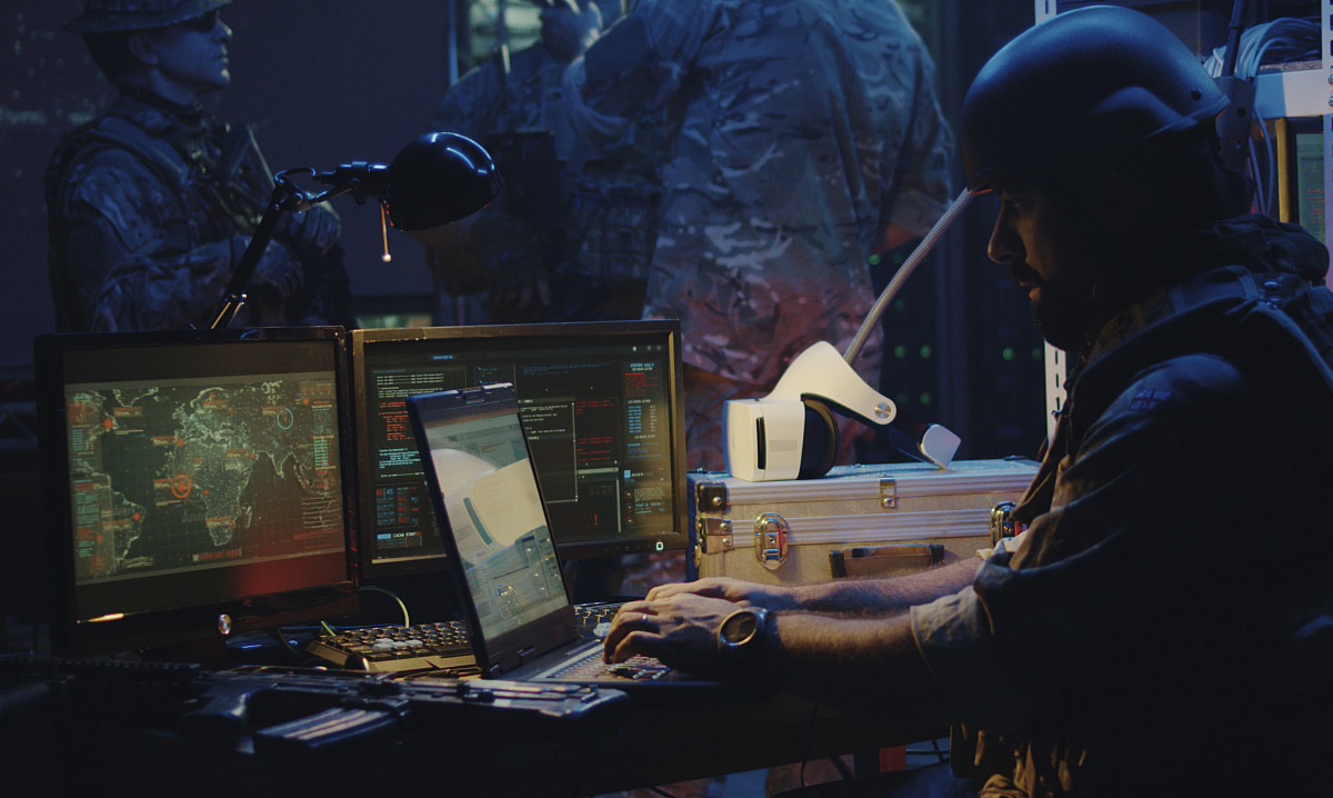 shot of a soldier working on a laptop in full combat gear