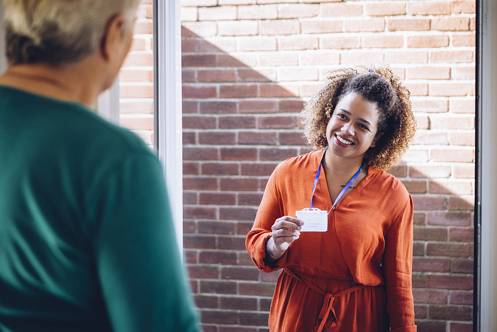 Social Work Career Social worker showing her badge at the front door of a senior womans home.