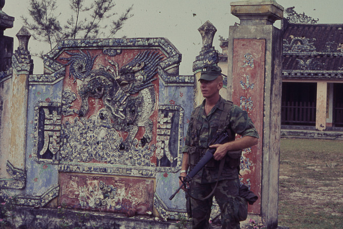 Don Griffis standing in front of a Vietnamese dragon mural