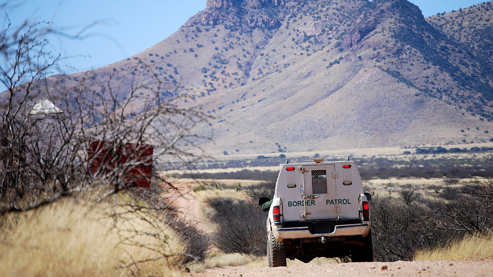 A border patrol vehicle driving through rocky terrain