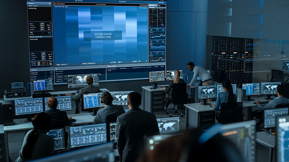 Security Studies and Criminal Justice - 1328842105 A group of people in a control room working on computers and analyzing data