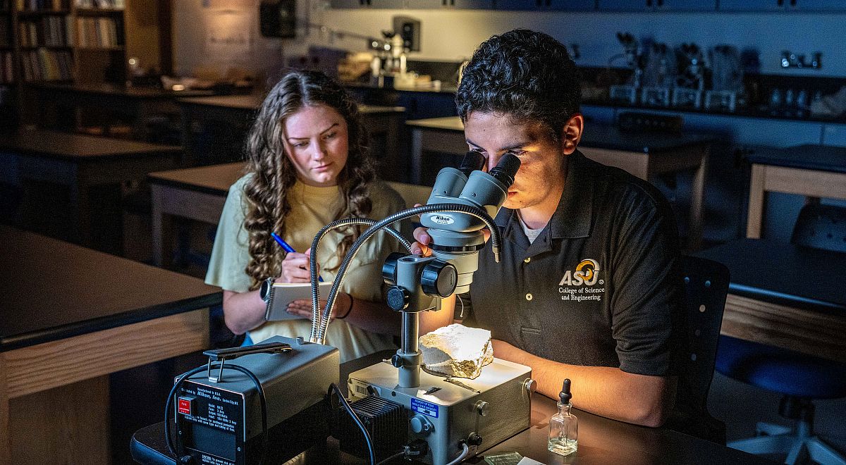 Two Angelo State Geoscience students studying a rock under a microscope