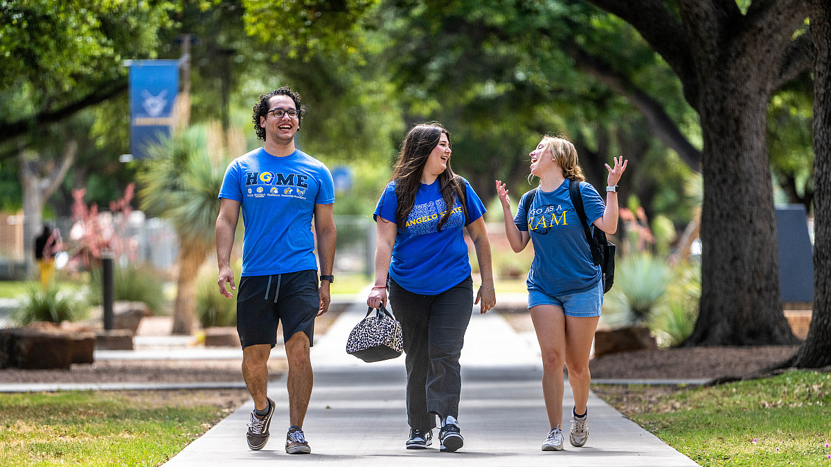 Three Angelo State students walking across campus talking to each other