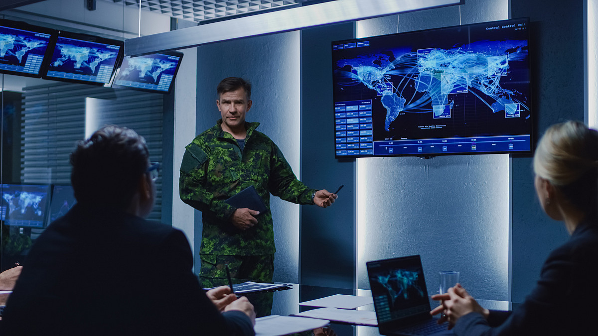 Military Man holds a Briefing to a team of government agents.