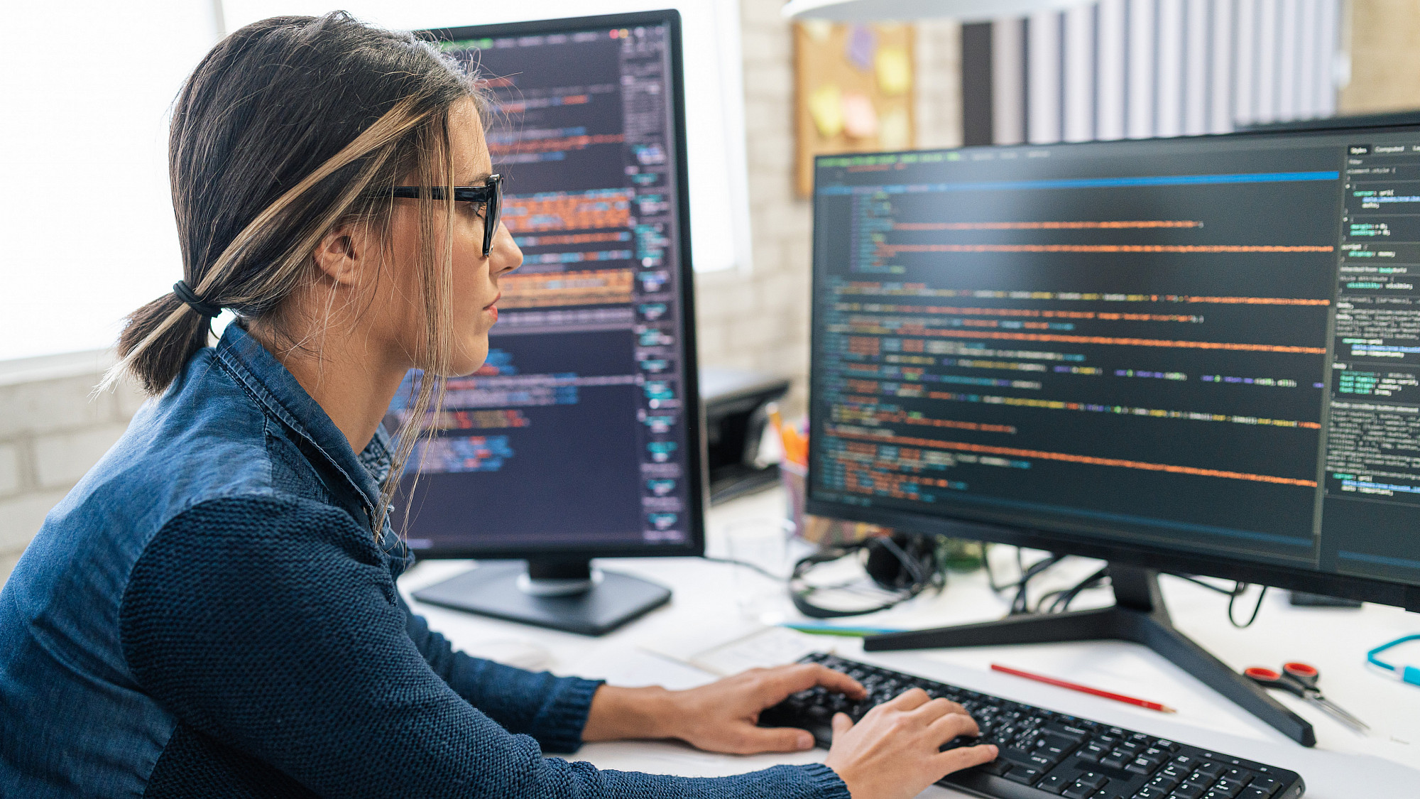 A freelance developer coding and programming on two screens.