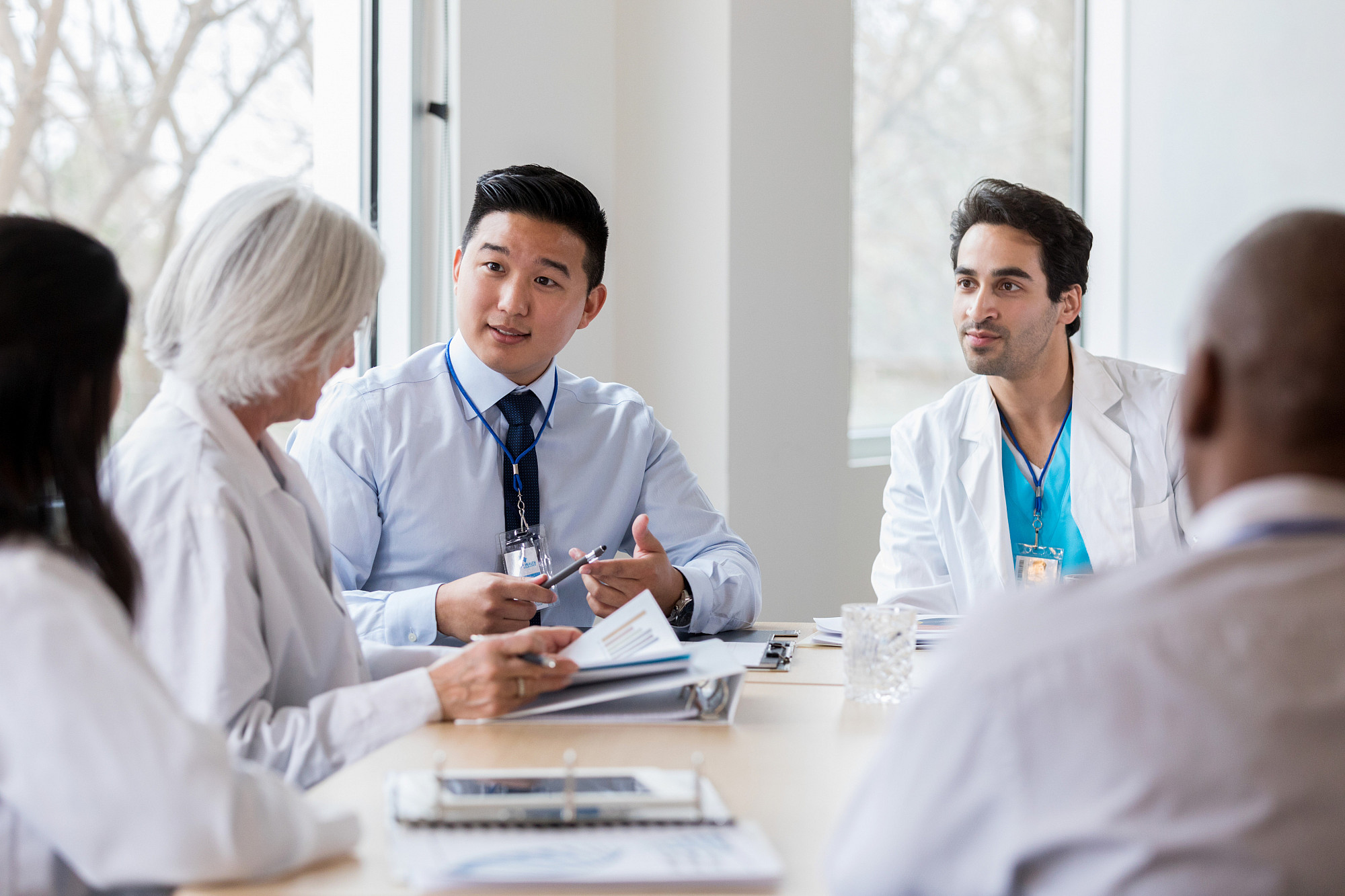 Male hospital administrator discusses hospital business with a female doctor during a staff meeting.