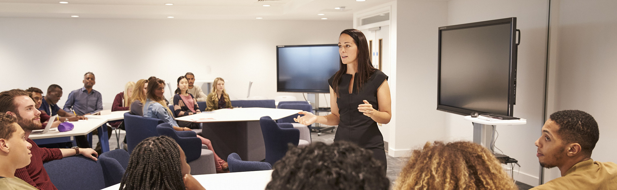Female teacher addressing university students in a classroom