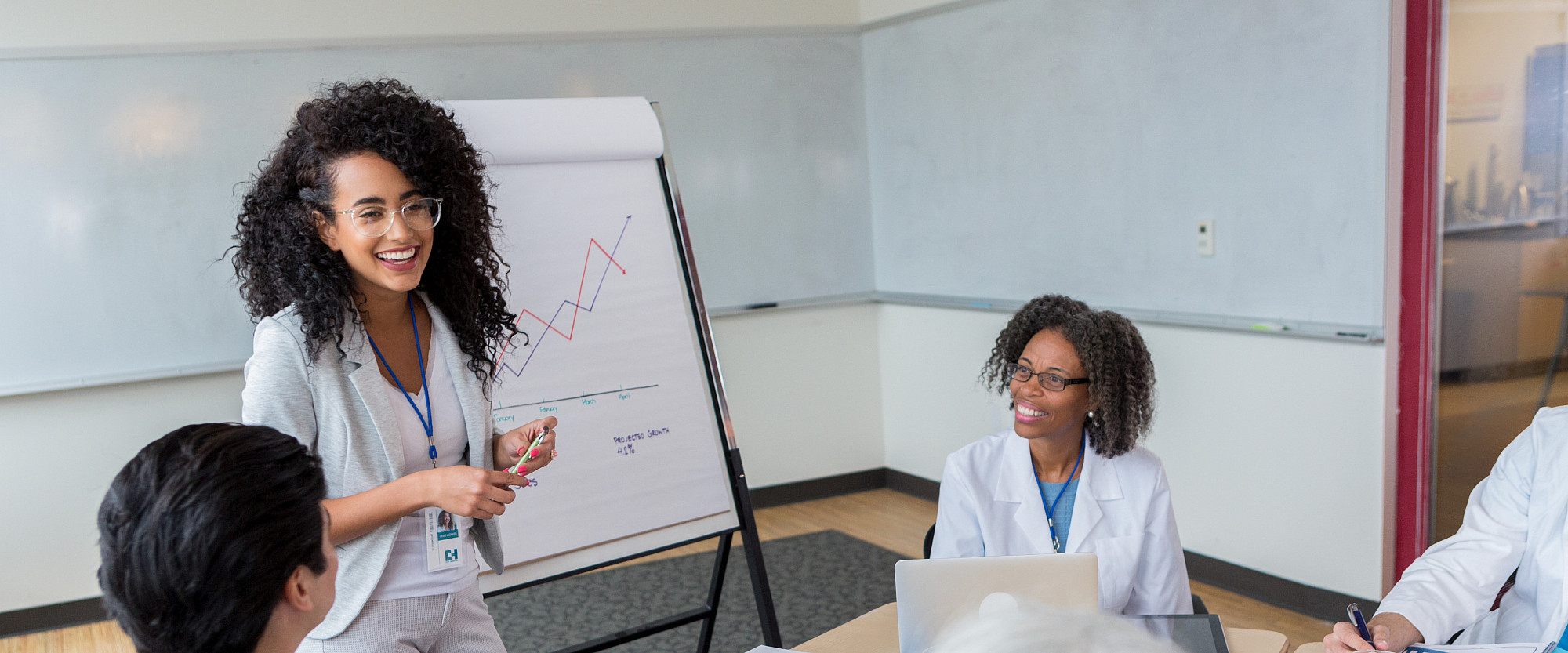 A female hospital administrator smiles while discussing hospital business with colleagues and healthcare providers.