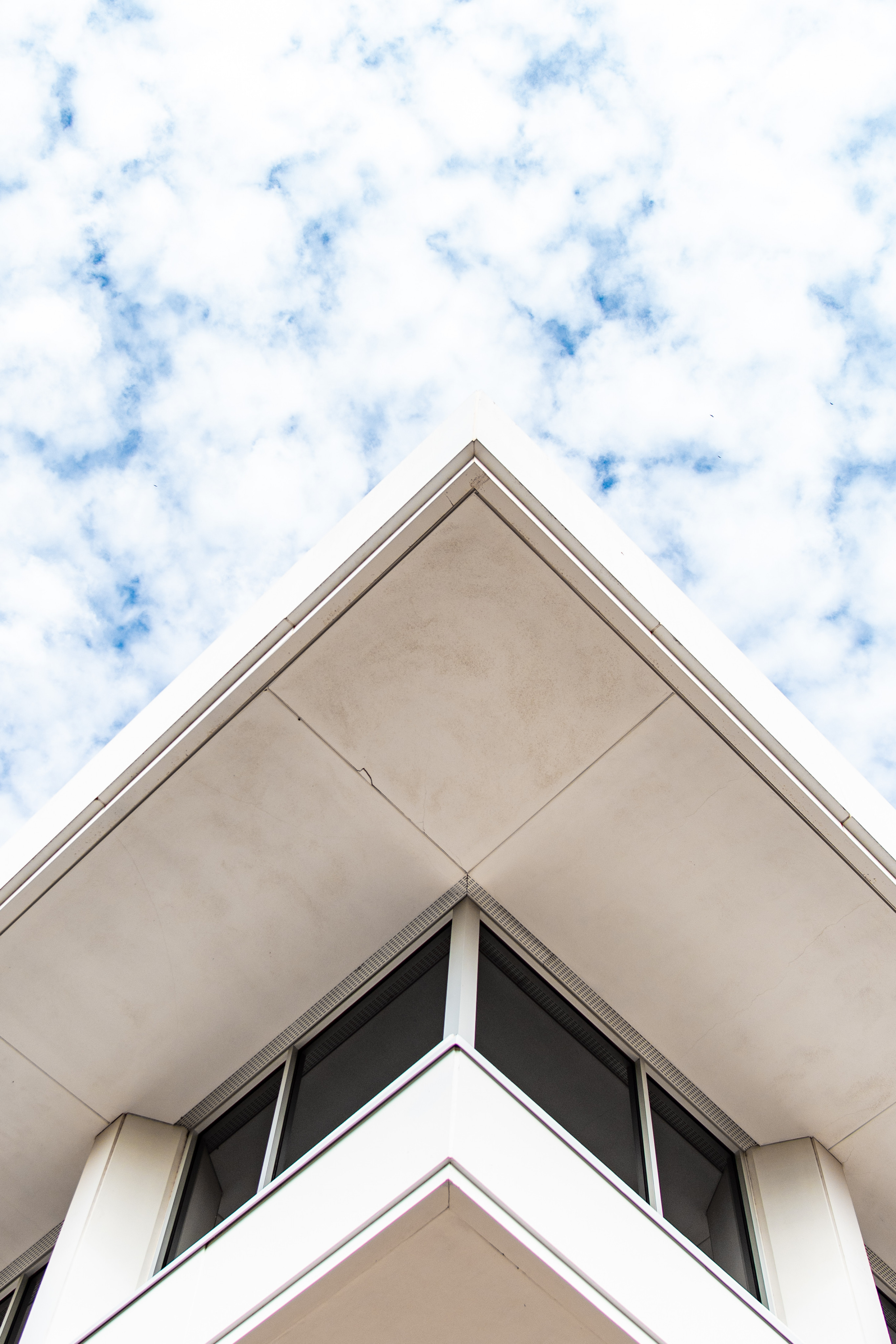 Looking up at the corner of a white building with windows
