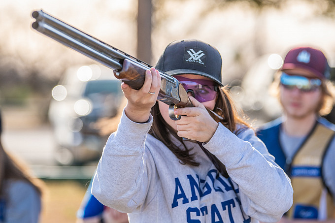 A student on the Shotgun Sports Team wearing an Angelo State sweatshirt aiming at a target