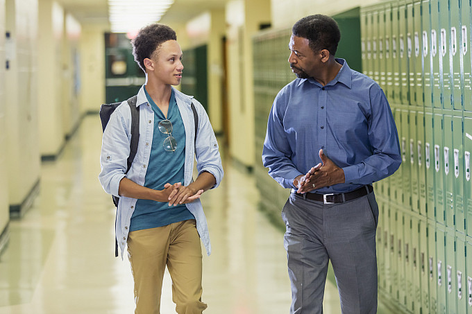 Principal and high school student walking in a hallway