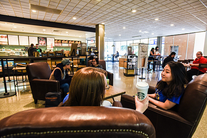 Students sitting on couches in Starbucks drinking coffee and talking.