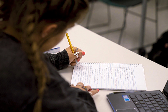 Student writing on a notepad in class