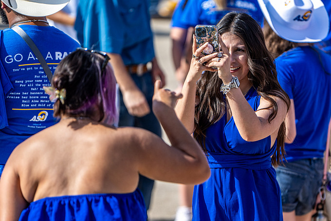Student taking a photo of a student holding up the ram hand.