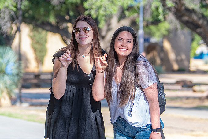 Two female students outside pose using the ram hand on the first day of school