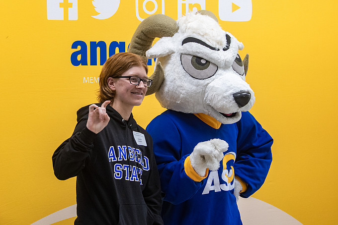 New student taking a picture with Roscoe, the mascot.