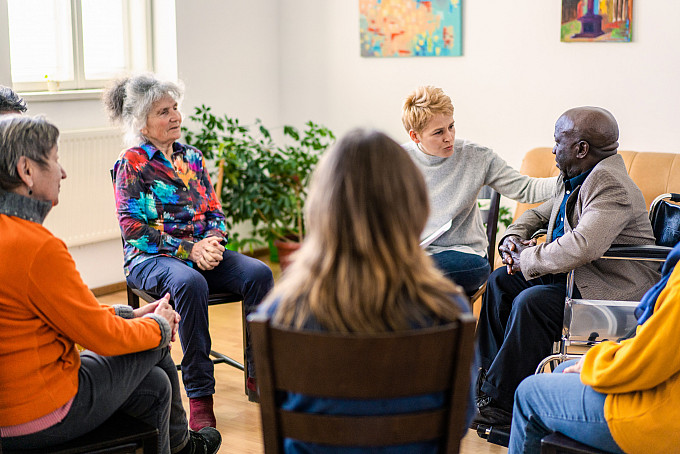 A female psychologist offers sympathy to a mature man while conducting a group therapy session