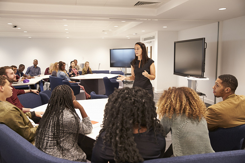 Communication 597959356 Female teacher addressing university students in a classroom