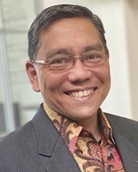 headshot of a man in a suit with glasses