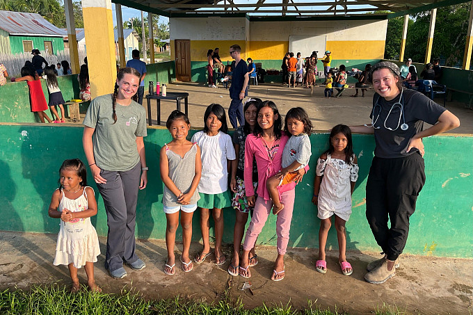 Honors students wearing a stethoscope in a foreign country with children